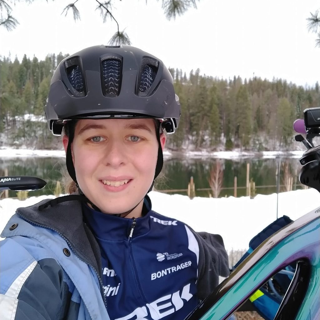Katie Kory headshot with her mountain bike by the river in winter snow